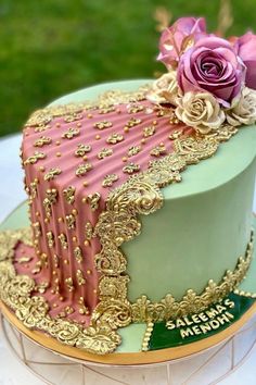 there is a cake that has pink and green frosting on it with gold trimmings