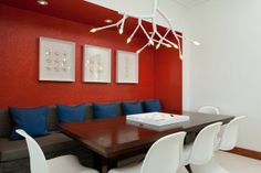 a dining room table with white chairs and blue pillows on the bench next to it