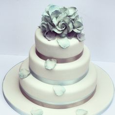 a three tiered cake with white frosting and blue flowers on top, sitting on a plate