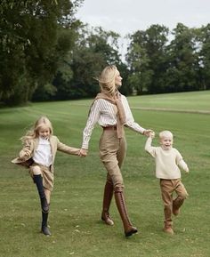 a woman and two children are walking in the grass with their arms around each other