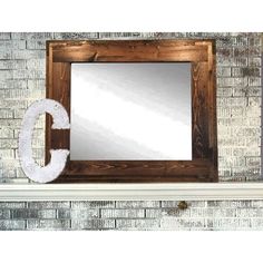 the letter c is placed in front of a brick wall with a mirror on it