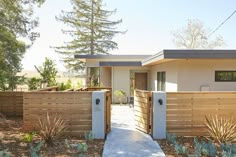 a house with wooden fence and plants in the front yard