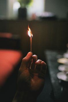 a person holding a lit matchstick in their hand with the light shining on them