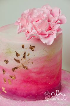 a pink and gold cake with flowers on top