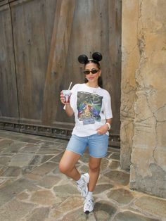 a woman in mickey mouse ears holding a drink