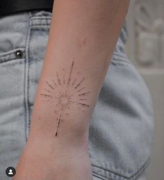 a woman's wrist with a small sun tattoo on the left side of her arm