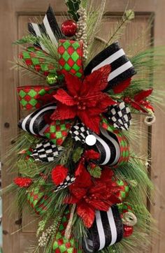 a christmas wreath hanging on the side of a door with red, green and black decorations