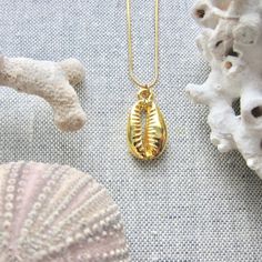 We love this fun and summery, beachy necklace. Answer the siren's song and get one for yourself or someone you love. Would make a great gift for the surfer or beach-lover in your life! A 14k gold electroplated cowrie shell dangles from a lustrous, high quality gold filled snake chain. The perfect summertime accessory! Chain: Gold fill, length 16" Cowrie Pendant: 22k Gold plated size: 26 x 18 mm✦ JEWELRY CARE ✦✧ Warm water and a soft cloth are the best thing you can do to maintain the beauty of y Gold Bohemian Shell For Festival, Gold Starfish Charm Necklace For Beach Season, Gold Necklace With Starfish Charm For Beach Season, Gold Charms Jewelry For Vacation, Gold Vacation Jewelry With Charms, Vacation Gold Jewelry With Charms, Gold Shell Necklace With Starfish Charm For Beach, Gold Shell Necklace With Starfish Charm For Summer, Beach Jewelry With Charms In Ocean-inspired Style