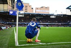 a man kneeling down on top of a soccer field next to a blue and white flag