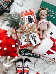 a teddy bear sitting on top of a blanket next to christmas decorations and gifts for the holiday season