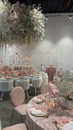 a banquet table set up with pink and white flowers hanging from it's ceiling