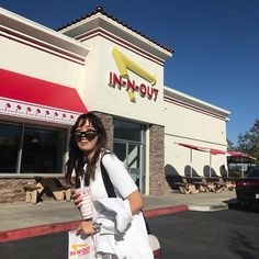 a woman in sunglasses is walking past a fast food restaurant