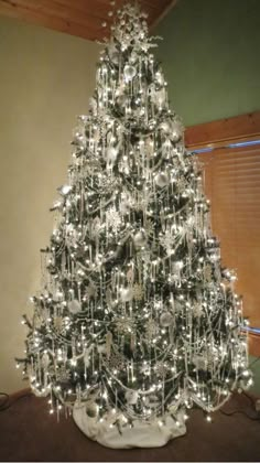 a silver christmas tree with lights and ornaments