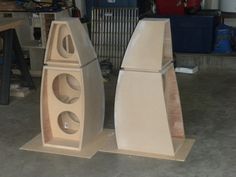 two wooden speakers sitting on top of each other in front of a workbench