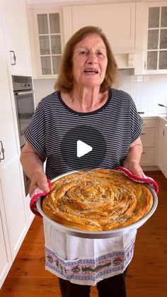 a woman holding a large pan filled with food