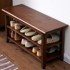 a wooden bench with several pairs of slippers on it and a rug in the corner