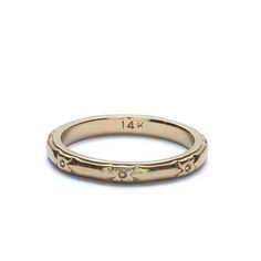 an 18k yellow gold wedding band with flowers on the side and four small diamonds in the middle