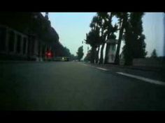 an empty street with trees on both sides and cars driving down the road at night