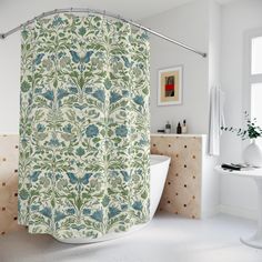 a bathroom with a bathtub, sink and shower curtain that has blue flowers on it