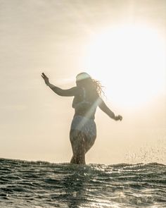 a woman riding a surfboard on top of a wave in the ocean at sunset