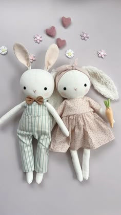 two stuffed animals laying next to each other on a gray surface with flowers in the background