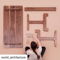 a woman is sitting on the floor next to some wooden pieces and she has her arms up