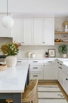 a kitchen with white cabinets and an island in the middle, surrounded by wicker chairs