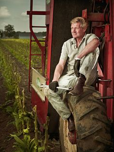 a man sitting on top of a tractor in a field