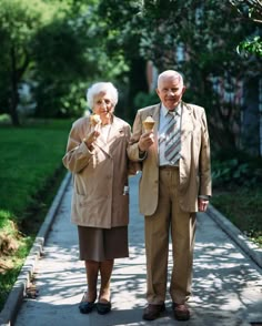 an older couple standing on a sidewalk holding wine glasses