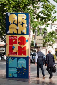 two men walking down the sidewalk next to a sign