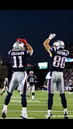 two football players standing on the field with their arms in the air and one holding his head