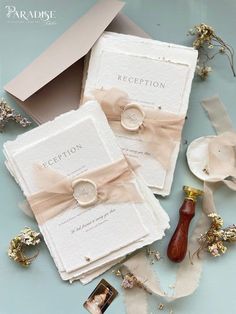 two wedding rings are sitting on top of some cards with ribbons and flowers around them