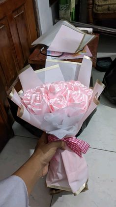 a person holding a bouquet of pink roses in their hand and wrapping it around the box