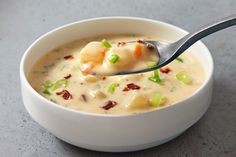 a white bowl filled with soup on top of a table next to a silver spoon