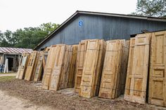 several wooden doors lined up in front of a black building with a blue sign on it