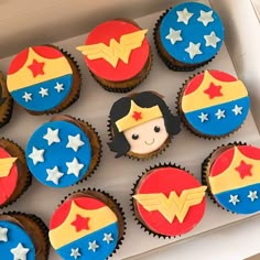 cupcakes decorated with icing in the shape of superman and wonder woman