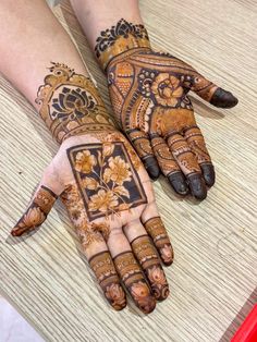 two hands with henna tattoos on them, one is showing the intricate design and the other has flowers