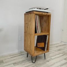 a small wooden shelf with some records on it's legs and a record player in the middle