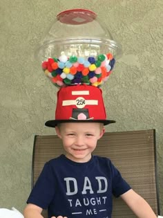 a young boy wearing a hat made to look like a gummy machine with balls on top