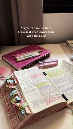 an open book sitting on top of a desk next to a pile of papers and pens