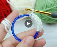 a person holding a yarn ball in front of some crochet balls and knitting needles