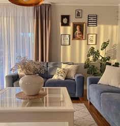 a living room filled with blue couches next to a window covered in curtains and pictures