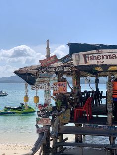 a small bar on the beach with signs hanging from it