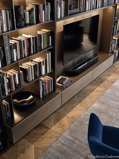 a living room filled with lots of books next to a flat screen tv mounted on a wall