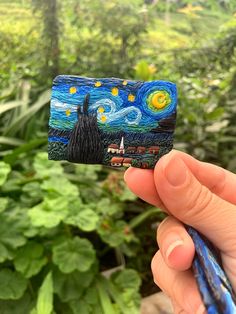 someone is holding up a piece of art that looks like the starry night painting