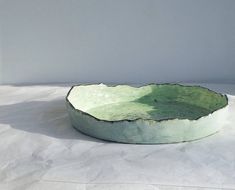 a green bowl sitting on top of a white table