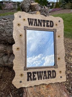 a wooden sign that says wanted reward sitting on top of a tree stump in front of a house