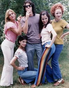 a group of people standing next to each other in front of some trees and bushes