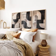 a bed with two pictures above it and pillows on the headboard next to each other