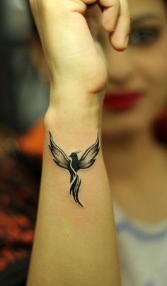 a woman's arm with a bird tattoo on the left side of her wrist